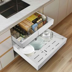 an open drawer in the middle of a kitchen with dishes and utensils on it