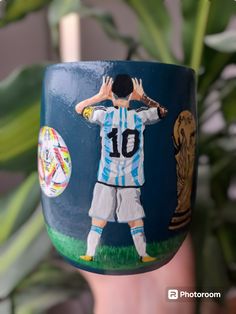 a close up of a cup with a soccer player painted on it