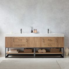 a bathroom vanity with two sinks and towels on the counter next to each other in front of a gray wall