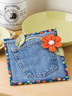 a blue jean pocket with a flower on it sitting next to a plate and bowl