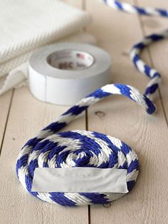 a blue and white striped rope next to a roll of tape on a wooden floor