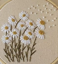 a close up of a embroidery on a hoop with white flowers and gold dots in it