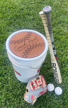 an autographed baseball bat, glove and ball in a bucket on the grass