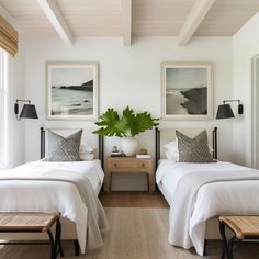 two beds in a bedroom with white walls and wood flooring next to each other