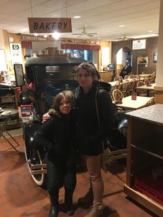 two women standing in front of an old car