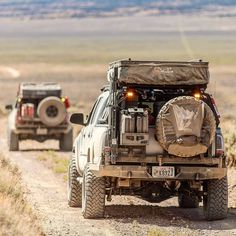 two jeeps driving down a dirt road in the desert