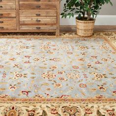 a blue rug with an ornate design on the floor next to a dresser and potted plant