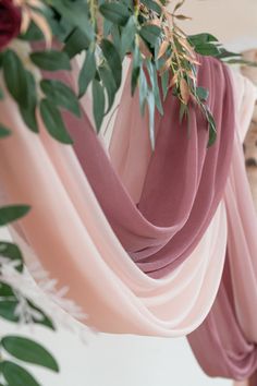 the fabric is hanging from the ceiling with flowers and greenery