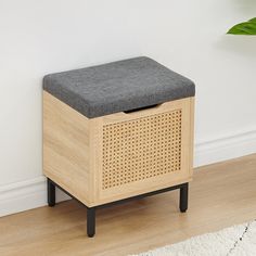 a wooden bench with a grey cushion on it in front of a white wall and wood floor