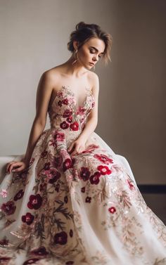 a woman is sitting on a couch wearing a dress with flowers in the front and back