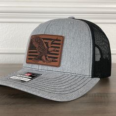 American Flag Eagle Patch Hat. Specifications: 🧢 Richardson original 112 trucker; adjustable for the perfect fit 🎩 60/40 cotton/polyester blend for comfort 📏 One size fits most 🏷️ Expertly laser engraved leatherette patch design 📦 Ships in 2 to 3 business days from our Orlando Studio Care Instructions: 🚫 Do not wash; spot clean only Please Note: 🌈 Colors may vary from photos based on your viewing screen. Adjustable Leather Baseball Cap With Leather Patch, Casual Leather Snapback Hat Adjustable, Black Leather Adjustable Snapback Hat, Leather Snapback Baseball Cap, Adjustable Leather Snapback Baseball Cap, Adjustable Leather Trucker Hat, Adjustable Baseball Cap With Leather Patch And Flat Brim, Leather Trucker Baseball Cap With Curved Bill, Adjustable Leather Snapback Hat