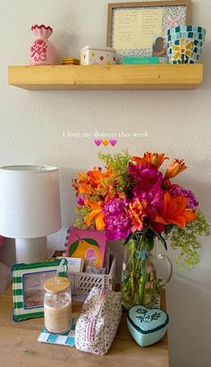 a wooden table topped with vases filled with flowers and other items next to a lamp