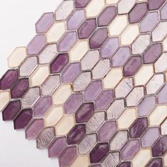 a purple and white mosaic tile pattern on the side of a wall with different colors