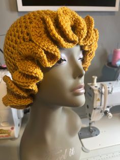 a mannequin head wearing a yellow knitted hat on top of a sewing machine