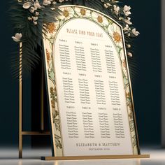 a wedding seating sign with flowers and greenery on it in front of a black background