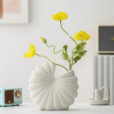 a vase with yellow flowers in it sitting on a table next to an old radio