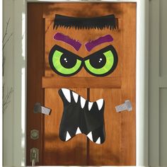 a door decorated to look like a monster with green eyes and fangs on it's face