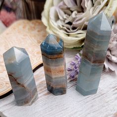 three blue and brown crystals sitting on top of a wooden table next to white flowers