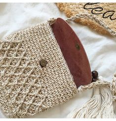 two purses with tassels on top of them sitting on a white surface