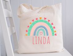 a canvas bag with the name lindaa on it and a rainbow in the background