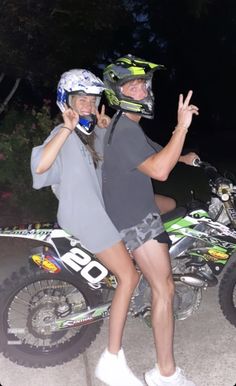 two people standing next to each other with helmets on and one holding up the peace sign