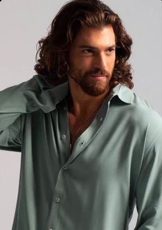 a man with long hair and beard wearing a green shirt is posing for the camera