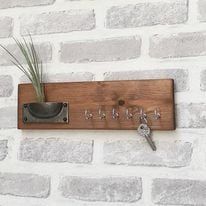 there is a key holder on the brick wall with a plant in it and two keys