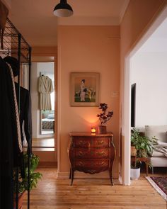 a room with a dresser, coat rack and pictures on the wall in front of it