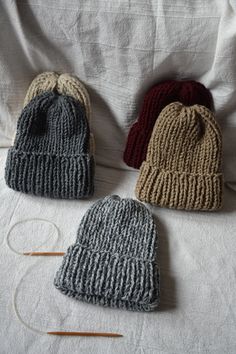 three knitted hats sitting on top of a bed