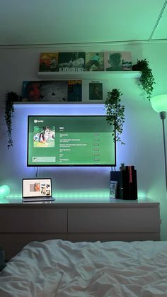 a bed with a laptop on top of it in front of a flat screen tv