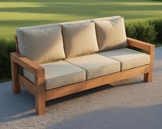 a wooden couch sitting on top of a gravel road next to a lush green field