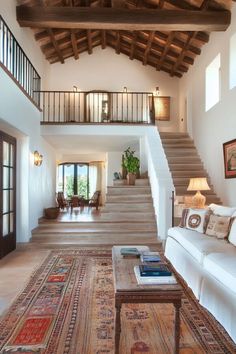 a living room filled with lots of furniture and a staircase leading up to the second floor