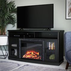 a flat screen tv sitting on top of a black entertainment center next to a fire place