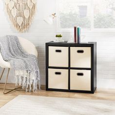 a white chair sitting next to a black and white storage unit on top of a hard wood floor