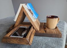 an open wooden box on top of a bed next to a cup