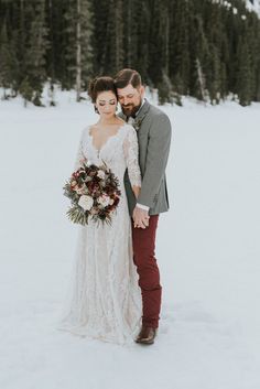 a bride and groom standing in the snow