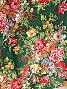 a green floral fabric with red, yellow and blue flowers on the bottom half of it