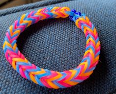 a close up of a colorful braided bracelet on a blue cloth material background,