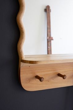 a wooden shelf with two knobs on it and a mirror in the back ground