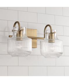 three light bathroom fixture with clear glass shades on the bottom and brass fixtures above it