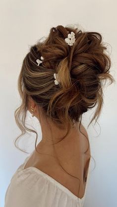 a woman with her hair in a low bun and flowers pinned to her head, looking off into the distance