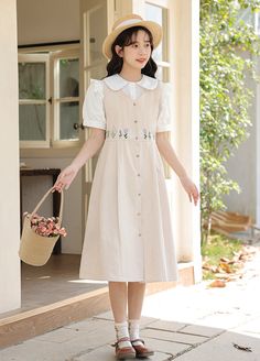 Button down dress with a v-neckline and wide sleeve holes for layering with your favorite blouses and sweaters. Embroidered wildflowers along the waistline with waist ties. Midi length. S: 36" chest and waist, 39" lengthM: 37.5" chest and waist, 39" lengthL: 39" chest and waist, 39.5" lengthXL: 40.5" chest and waist, 39.5" length Beige Button Dress For Spring, Beige Buttoned Dress For Spring, Spring Dresses With Buttons For Garden Party, Spring Garden Party Dress With Buttons, Spring Cottagecore Daywear Dresses, Cottagecore Dresses For Spring Day Out, Spring Daywear Dresses With Buttons, Pastoral Cotton Spring Dresses, Cottagecore Dresses With Buttons For Garden Party