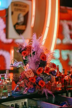 an arrangement of flowers and liquor bottles on a bar