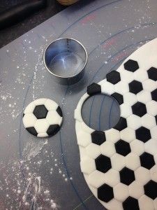 a cake with soccer balls on it sitting next to a bowl and measuring spoons