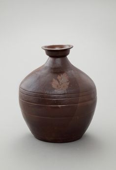 a brown vase sitting on top of a white table