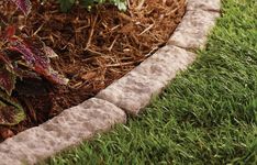 a close up of a flower bed in the grass with mulch and dirt around it