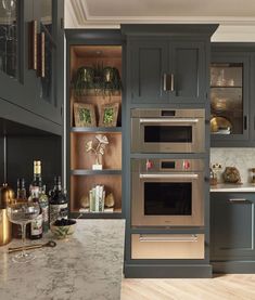 a kitchen with gray cabinets and marble counter tops, an oven built into the wall