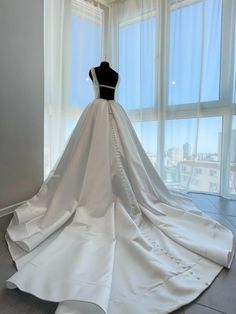 a wedding dress on display in front of large windows