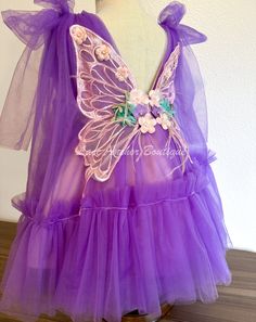 Flutter into summer with this vibrant purple girls dress! Adorned with flowers, butterflies, and playful wings on the back, this tulle dress is sure to make your little one feel like a fairy. The cute tied bow shoulder adds the perfect finishing touch to this dreamy dress. Size 3T Zip closure on back Purple Fairy Dress Toddler, Butterfly Baby Dress Fairy Wings, Purple Fairy Wings, Pageant Ooc, Wing Dress, Flower Girl Outfits, Strawberry Outfit, Purple Girls Dress, Purple Fairy