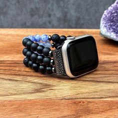 Transform your Apple Watch into a striking statement piece with our handcrafted Black Matte Onyx, Black Volcanic Lava, and Blue Cracked Agate gemstone watch band. Designed to blend versatility with elegance, this band fits all Apple iWatch Series 1/2/3/4/5/6/7/8/9/SE and Ultra, accommodating various sizes including 38mm/40mm/41mm and 42mm/44mm/45mm/49mm. Each band is meticulously crafted with high-quality Black Matte Onyx, Black Volcanic Lava, and Blue Cracked Agate beads, providing a sophisticated touch while ensuring a comfortable fit. Personalize the band length for a perfect fit around your wrist, enhancing both style and comfort. Suitable for both men and women, this unique watch band turns your Apple Watch into a stunning piece of jewelry, making it an exceptional gift for any occasi Adjustable Black Beaded Apple Watch Band, Black Wearable Art Bracelet, Black Bracelet Strap Apple Watch Band As Gift, Elegant Black Apple Watch Band For Gift, Elegant Black Apple Watch Band Gift, Handmade Black Watch Accessories For Gift, Handmade Black Watch Bands As Gift, Handmade Black Watch Accessories As Gift, Modern Apple Watch Band As Gift